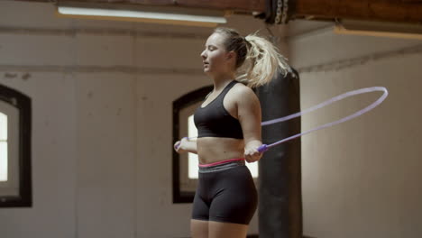 Medium-shot-of-focused-Caucasian-woman-jumping-rope-in-gym